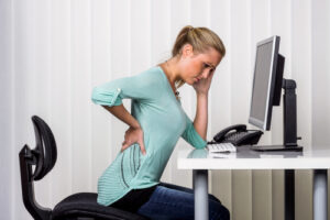 a spinal Injury Lawyer Milwaukee, WI woman with back pain at her desk
