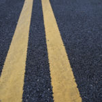 Hazardous Roadways & Personal Injury - Closeup asphalt road with marking lines for giving directions, traffic lines concept