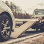 Common Causes Of Holiday Car Accidents - Loading broken car on a tow truck on a roadside