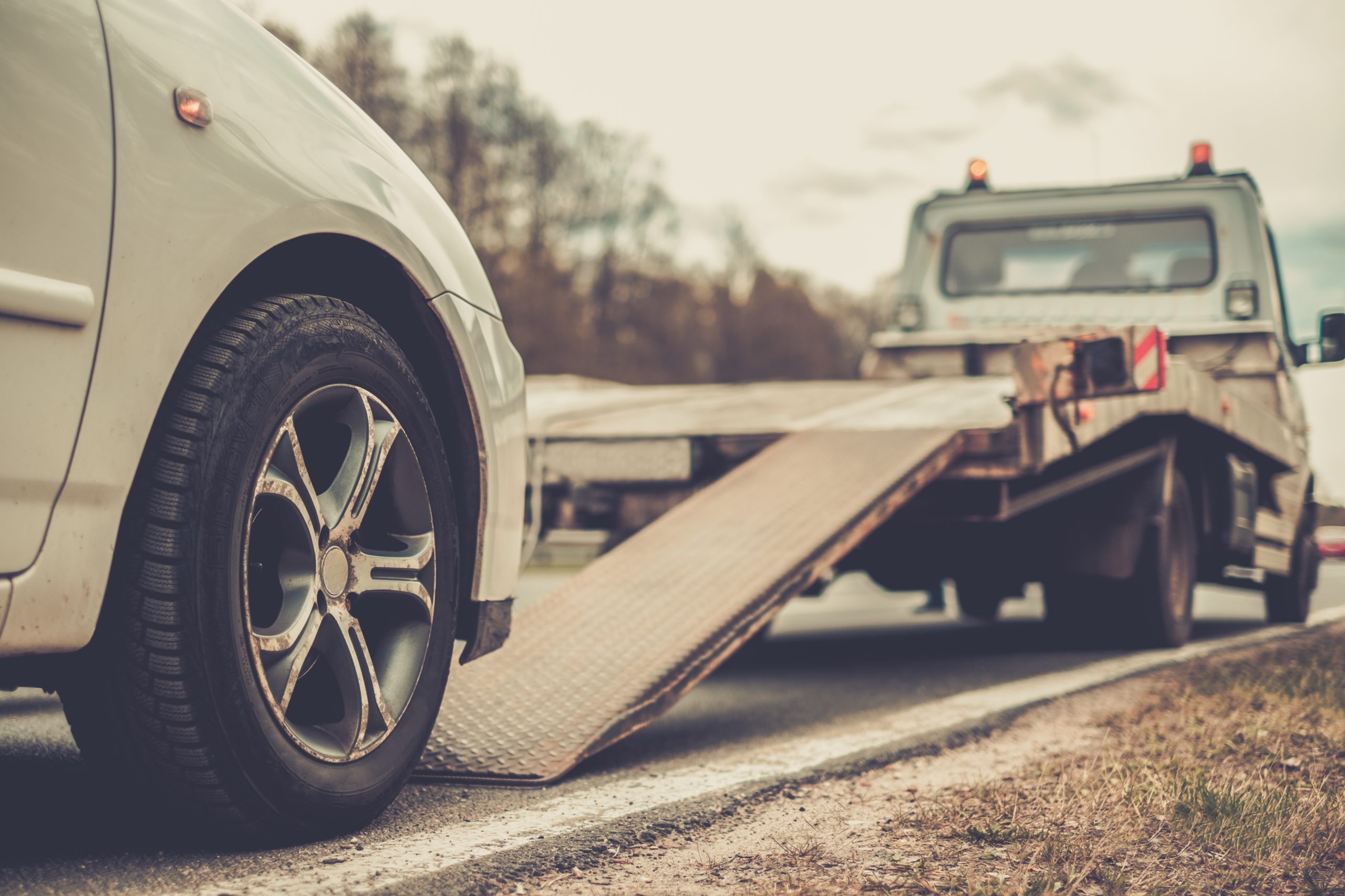 Common Causes Of Holiday Car Accidents - Loading broken car on a tow truck on a roadside